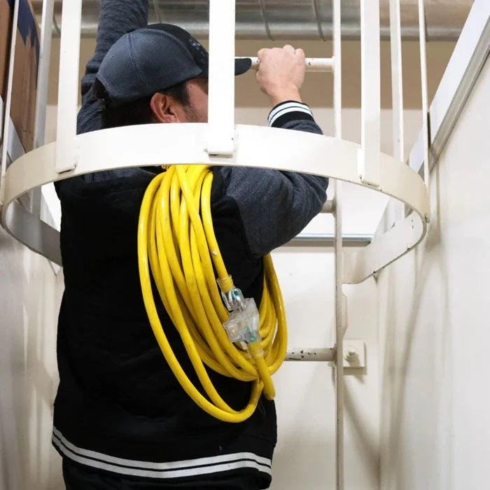Man With A DuroMax 50-Foot 10 Gauge Triple Tap Extension Power Cord Hanging Over His Shoulder While He Climbs Stairs