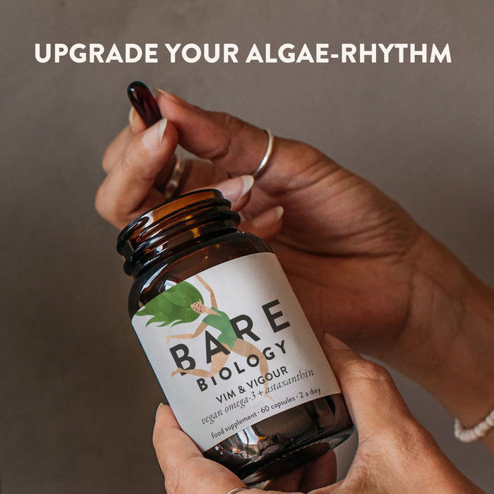 Bottle of Bare Biology Vim and VIgour supplement held by a hand with text 'Upgrade Your Algae-Rhythm' on a neutral background